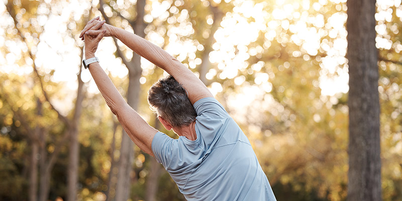 Fitness, park and stretching with a senior woman doing a warm up outdoor for exercise or a workout. Nature, health and training with a mature female back outside in a garden for a healthy lifestyle