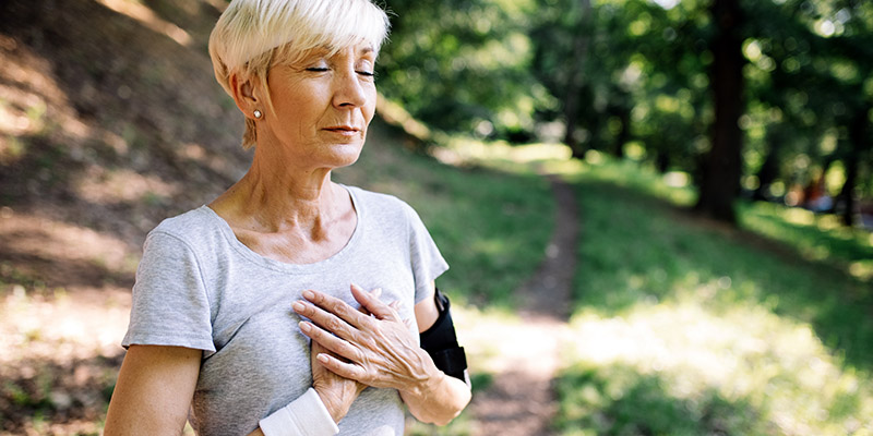 Senior woman with chest pain suffering from heart attack during jogging