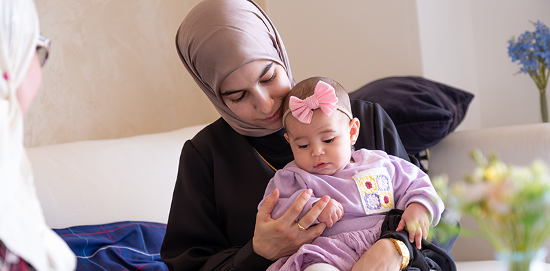 A South Asian mother with her baby sitting on her lap