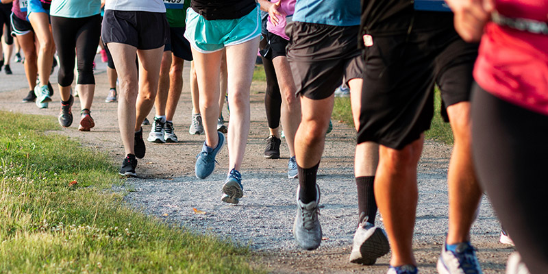 Legs of runners on a dirt path running a 5K race