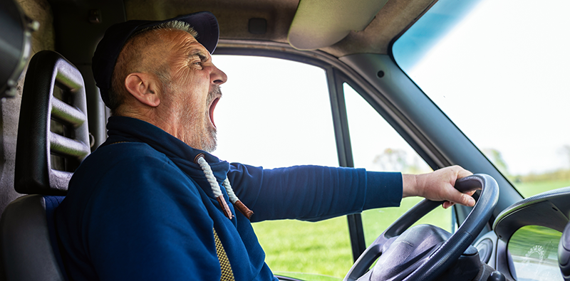 A truck driver yawning while driving