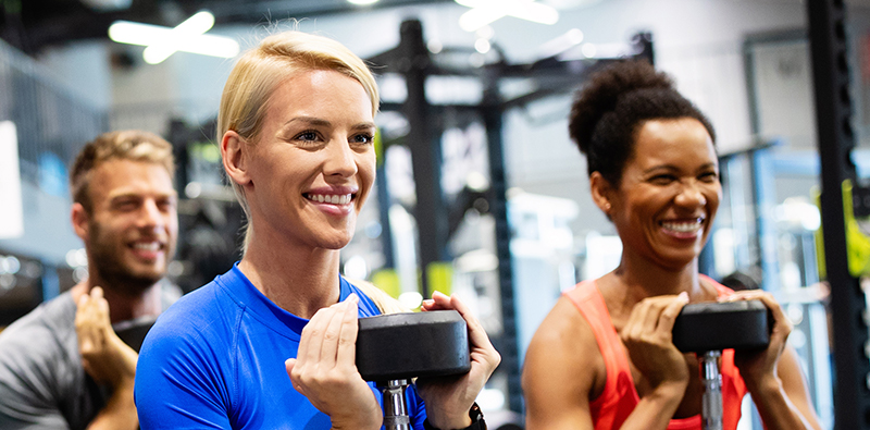 Two women lifting weights in a gym