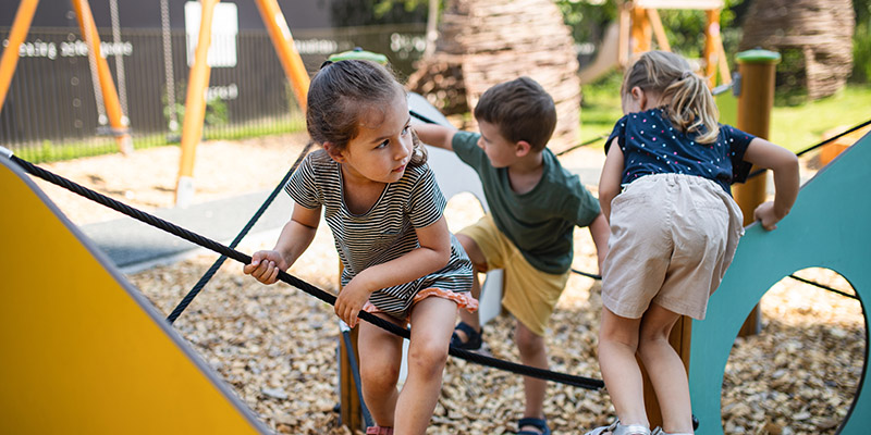 Group of small nursery school children playing outdoors on playground.