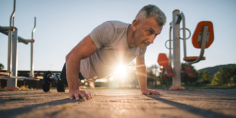 Active senior athlete doing push-ups in the open outdoor gym